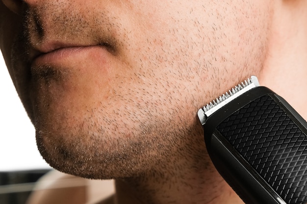 Man snijdt zijn baard met een elektrische trimmer