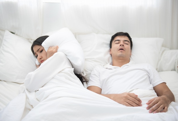 Man snoring, woman can not sleep in bed at home.
