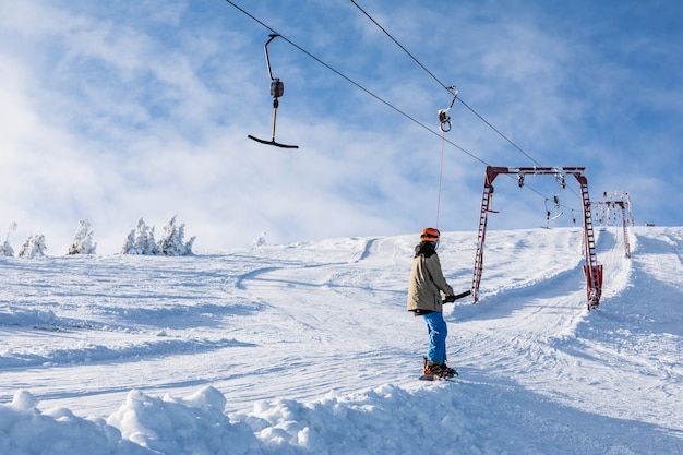 Man snowboarder die skijuk gebruikt om op de top van de wintersport van de bergen te komen