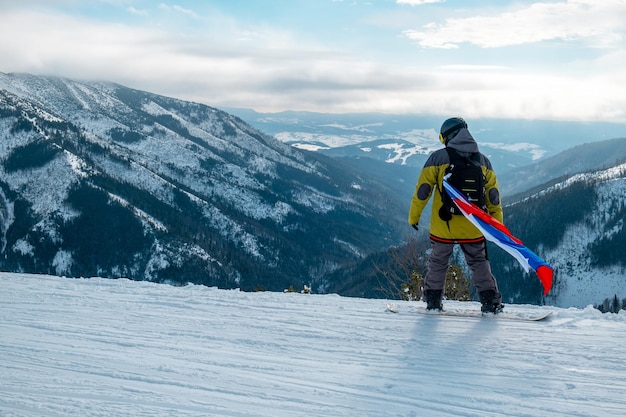 Man snowboarder met vlag van slowakije op de helling van het skioord