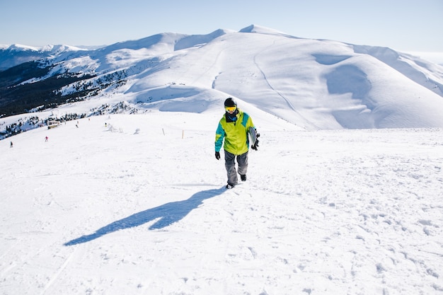 Man snowboarder at the top of the mountains beautiful view on background