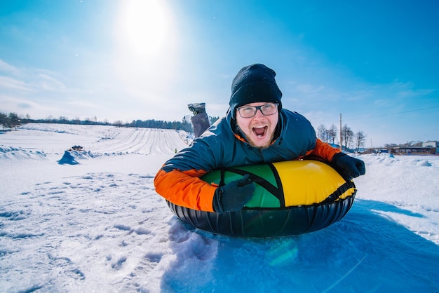 Man snowtubing van heuvel winteractiviteit