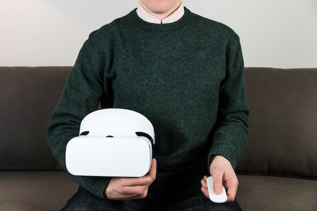 Man on sofa holding VR box and remote control