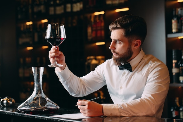 Foto man sommelier rode wijn proeven in de kelder