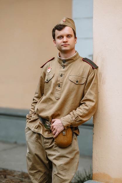 Un uomo in uniforme sovietica della seconda guerra mondiale si trova sul muro giallo