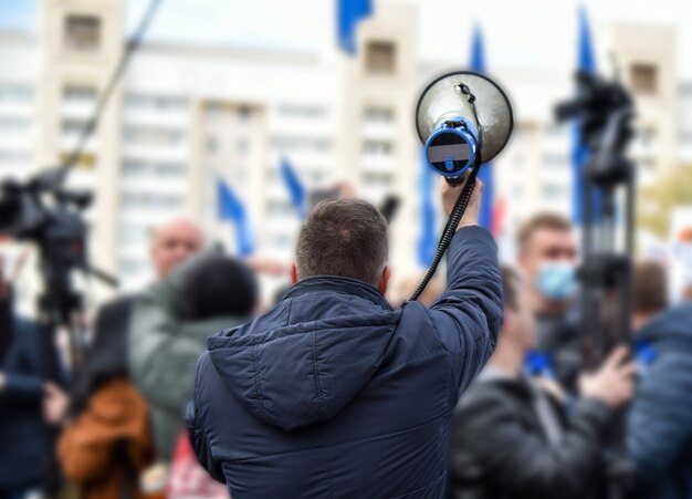 Мужчина говорит через громкоговоритель на митинге.