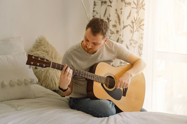 Man speelt een akoestische gitaar in een kamer thuis