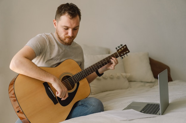 Man speelt een akoestische gitaar in een online les