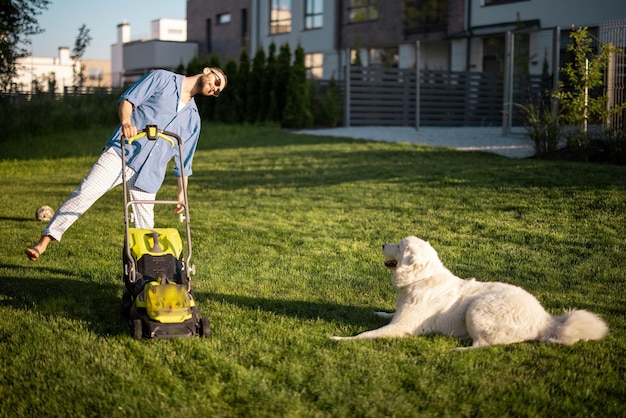 Man speelt met hond terwijl hij gazon in achtertuin verplaatst