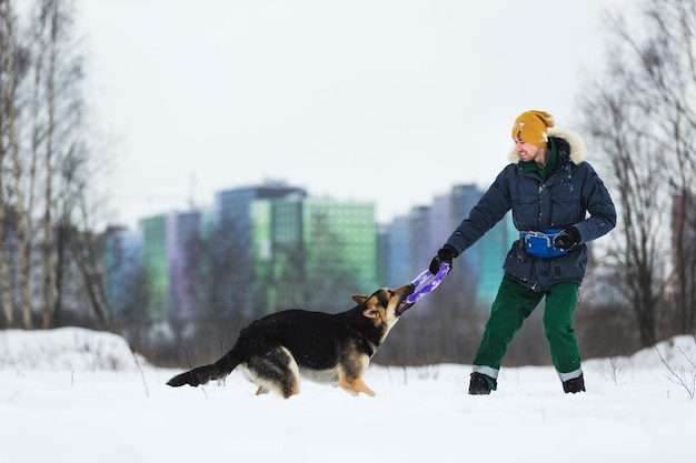 Man spelen met een Duitse herder in het park in de winter