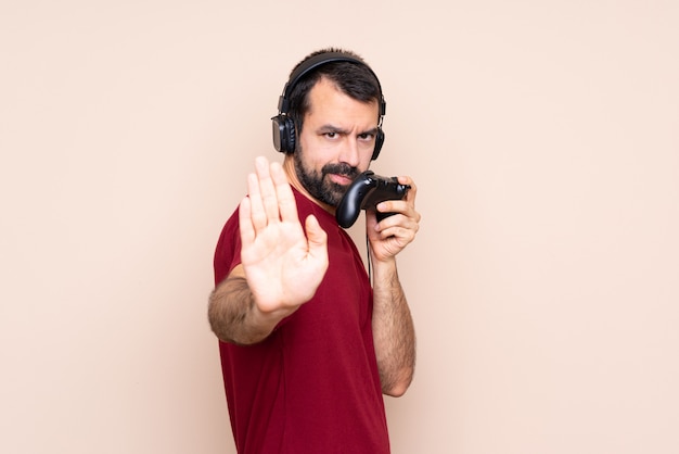 Man spelen met een video game controller over geïsoleerde muur maken stop gebaar en teleurgesteld