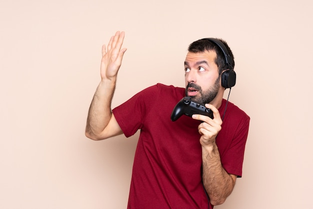 Man spelen met een video game controller over geïsoleerde muur nerveus en bang