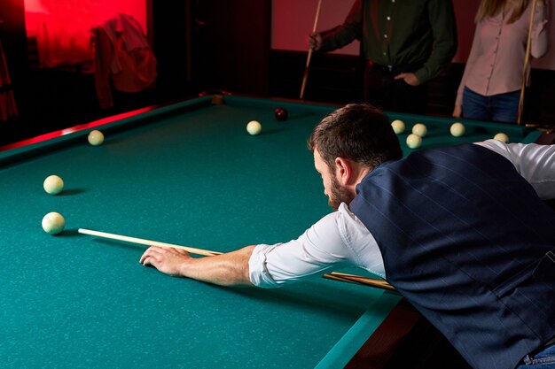 Man spelen snooker, voering om bal op poolbiljarttafel te raken. aangenaam tijdverdrijf in de bar na het werk