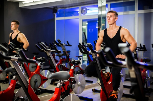 Photo man spinning on a bicycle at a gym