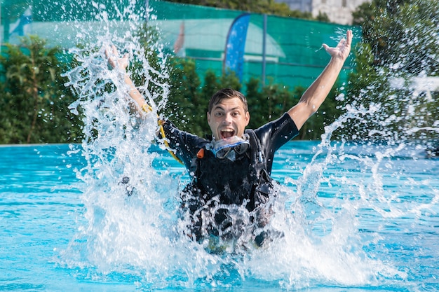 A man splashes in the pool while wearing a diving suit