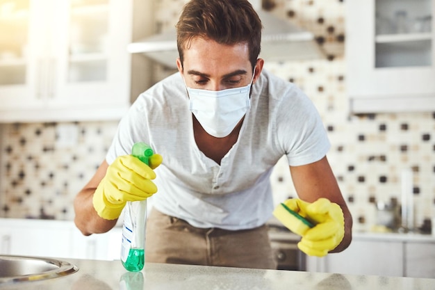 Man sponge and spray for cleaning in kitchen disinfect and chemical for washing counter in home Male person face mask and housekeeper service for dust bacteria and liquid to sanitize for hygiene