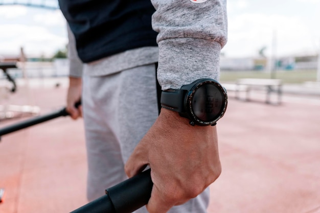 Man sport in het stadion, een atleet doet een oefening in een close-up van een smartwatch-polshorloge