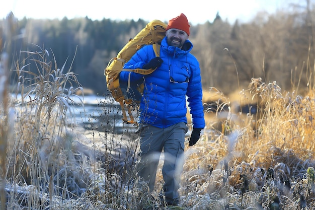 man in sports down jacket landscape winter trekking / down jacket on a tourist, outdoor activities in the north, seasonal landscape