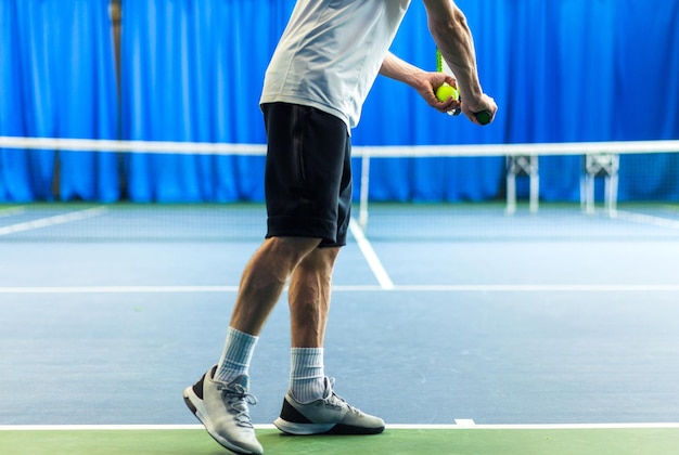 Foto un uomo in uniforme sportiva sta con le spalle alla telecamera tiene una racchetta e una palla nelle sue mani e sta per servire la foto orizzontale