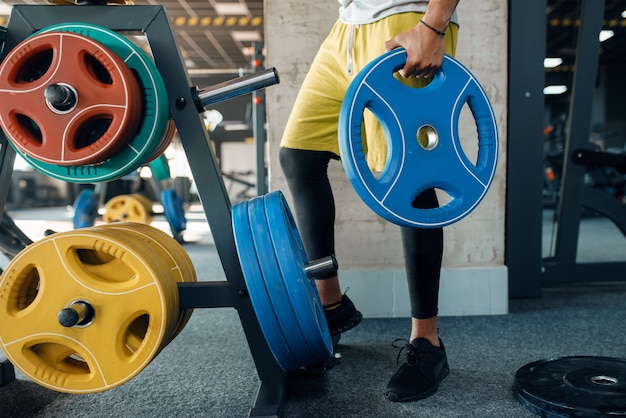 Man in sportswear doing exercise with wights on training in gym. Workout in sport club, healthy lifestyle