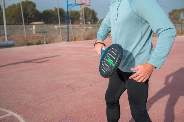 Man in sportswear holds a racket and plays paddle tennis