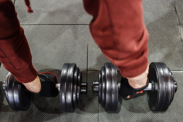 Man in sportswear pumping iron dumbbells