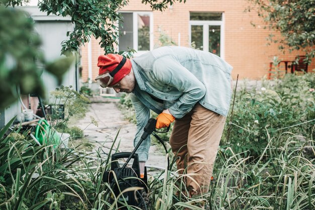 Man spraying aphids affected tree with insecticidal soap, agricultural worker spraying toxic pesticides or insecticides on fruit growing plantation