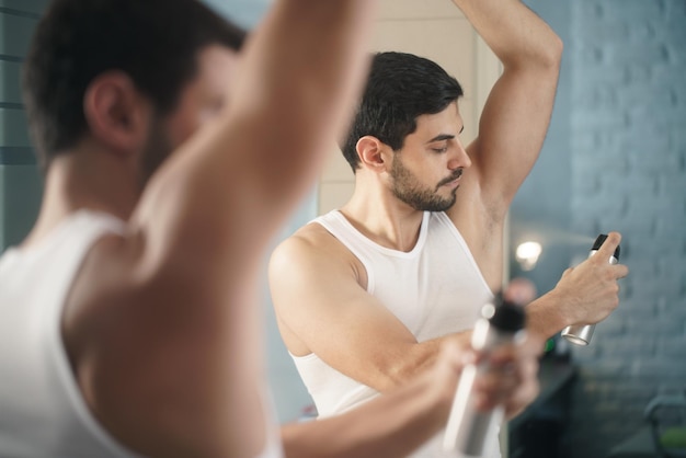 Photo man spraying deodorant on body at home