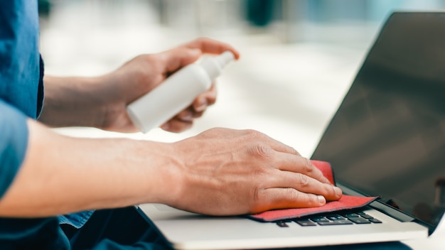 man spraying spray on the surface of a laptop