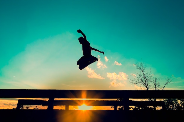 Foto man springen brug bij zonsondergang