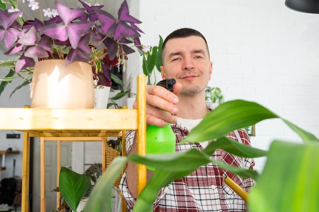 Man spuit uit een spuitpistool huisplanten uit haar collectie met liefde gekweekt op planken in het interieur van het huis Thuisplant groeit kas waterhuishouding bevochtiging