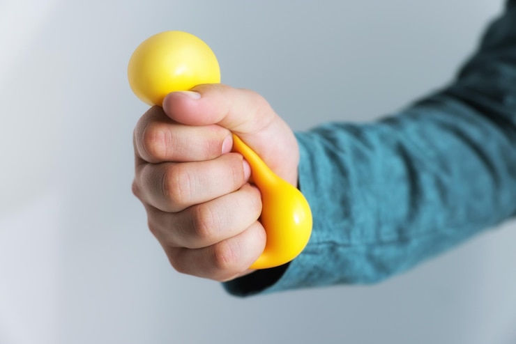 Photo man squeezing antistress ball on grey background closeup