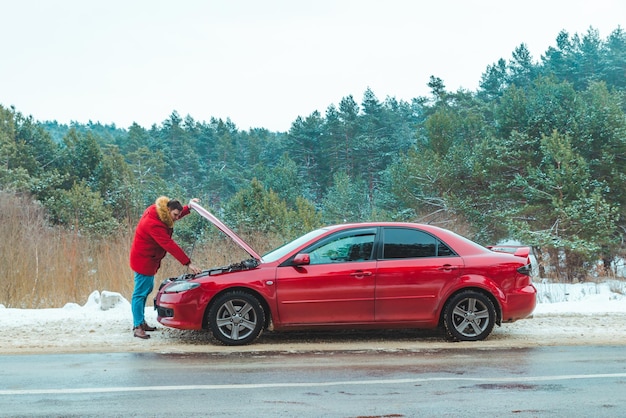 Man staande in de buurt van kapotte auto langs de weg besneeuwd winterweer