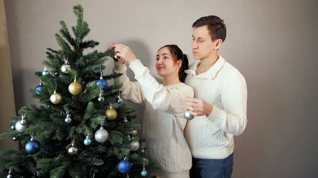 Man staat achter dame helpt kerstboom versieren