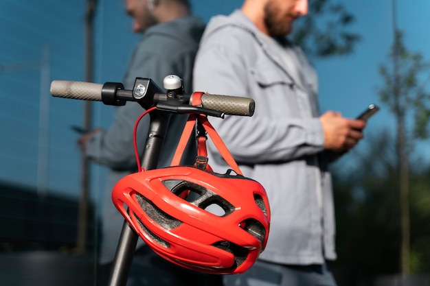 Man staat naast zijn scooter terwijl hij op zijn telefoon kijkt