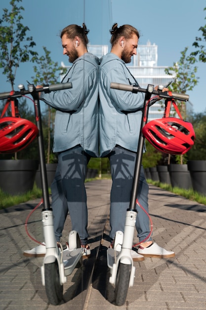 Man staat naast zijn scooter terwijl hij op zijn telefoon kijkt