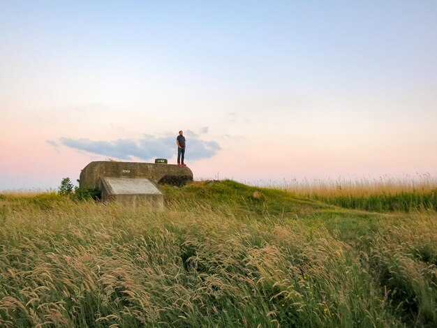 Foto man staat op een opslagtank boven het veld tegen de lucht