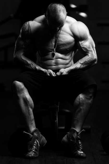 Man staat sterk in de sportschool en buigt spieren Gespierde atletische bodybuilder Fitness Model poseren na oefeningen