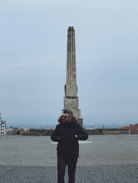 Foto man staat tegen een toren in de stad.