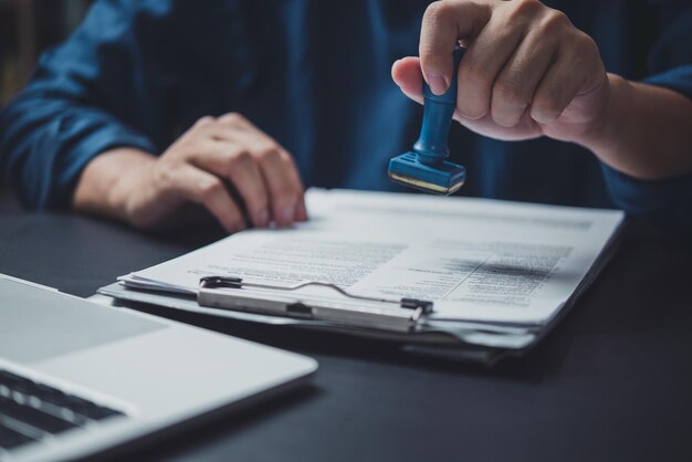 Foto uomo che timbra l'approvazione di documenti bancari di finanziamento del lavoro o di marketing di investimento sulla scrivania