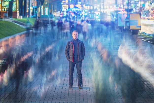 L'uomo sta nel flusso della folla. sera notte