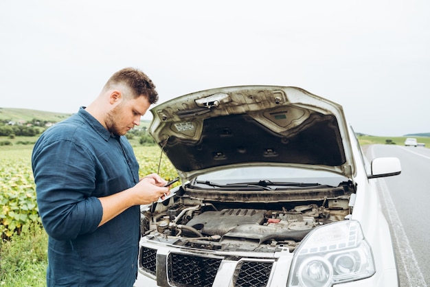 Man stand in front of broken car