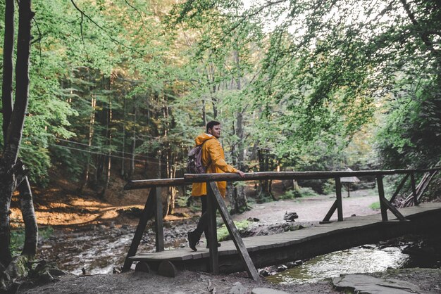 Photo man stand in the middle of forest in yellow raincoat hiking concept