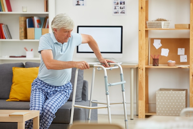 男は歩行器の助けを借りて立ち上がる