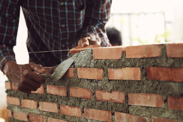 Foto uomo in piedi contro un muro di mattoni