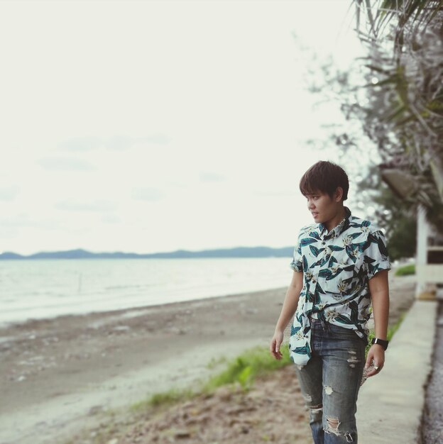 Photo man standing against sea at beach