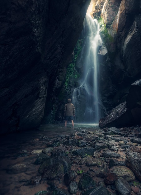 man standing against waterfall