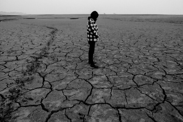 Photo man standing on barren drought affected field