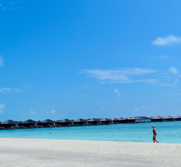 Man standing on beach against blue sky