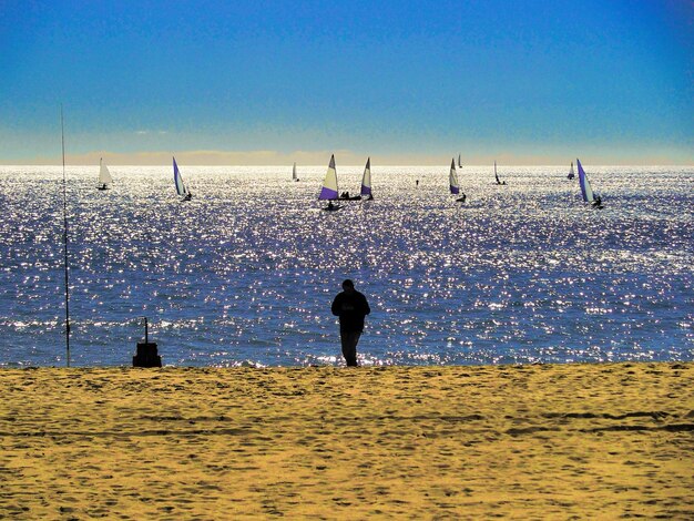 Foto uomo in piedi sulla spiaggia contro un cielo blu limpido